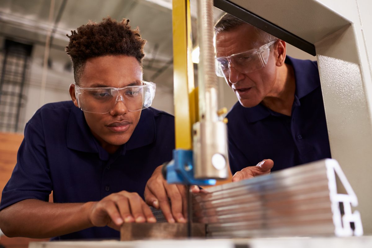 Two men in safety googles working at machine